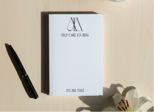 Self-care journal with a pen and coffee cup on a light surface